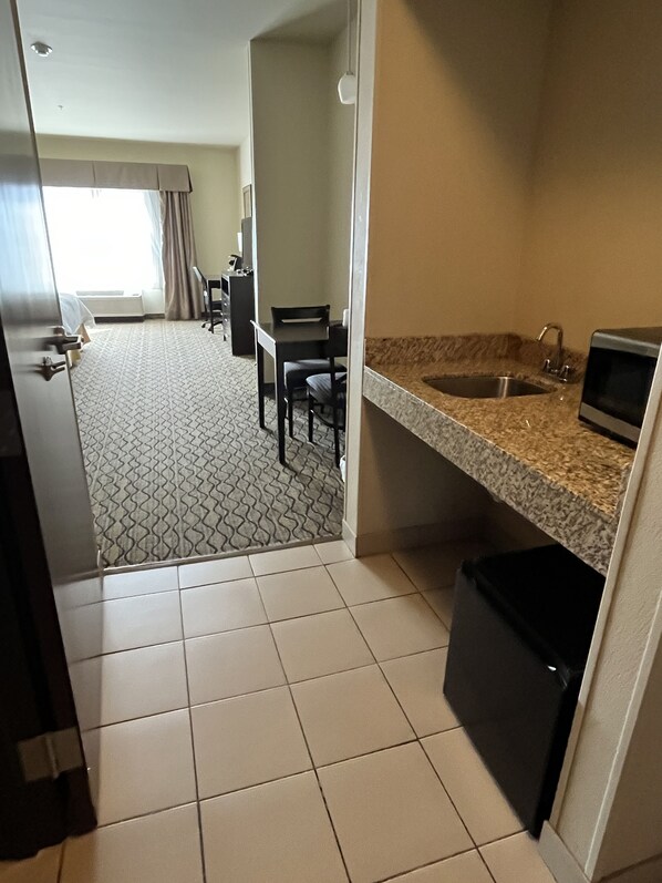 A compact hotel room with a kitchenette, a dining area with a table and chairs, and a bathroom with a sink and toilet. - Holiday Inn Express Hotel & Suites Deming Mimbres Valley by IHG (Deming)