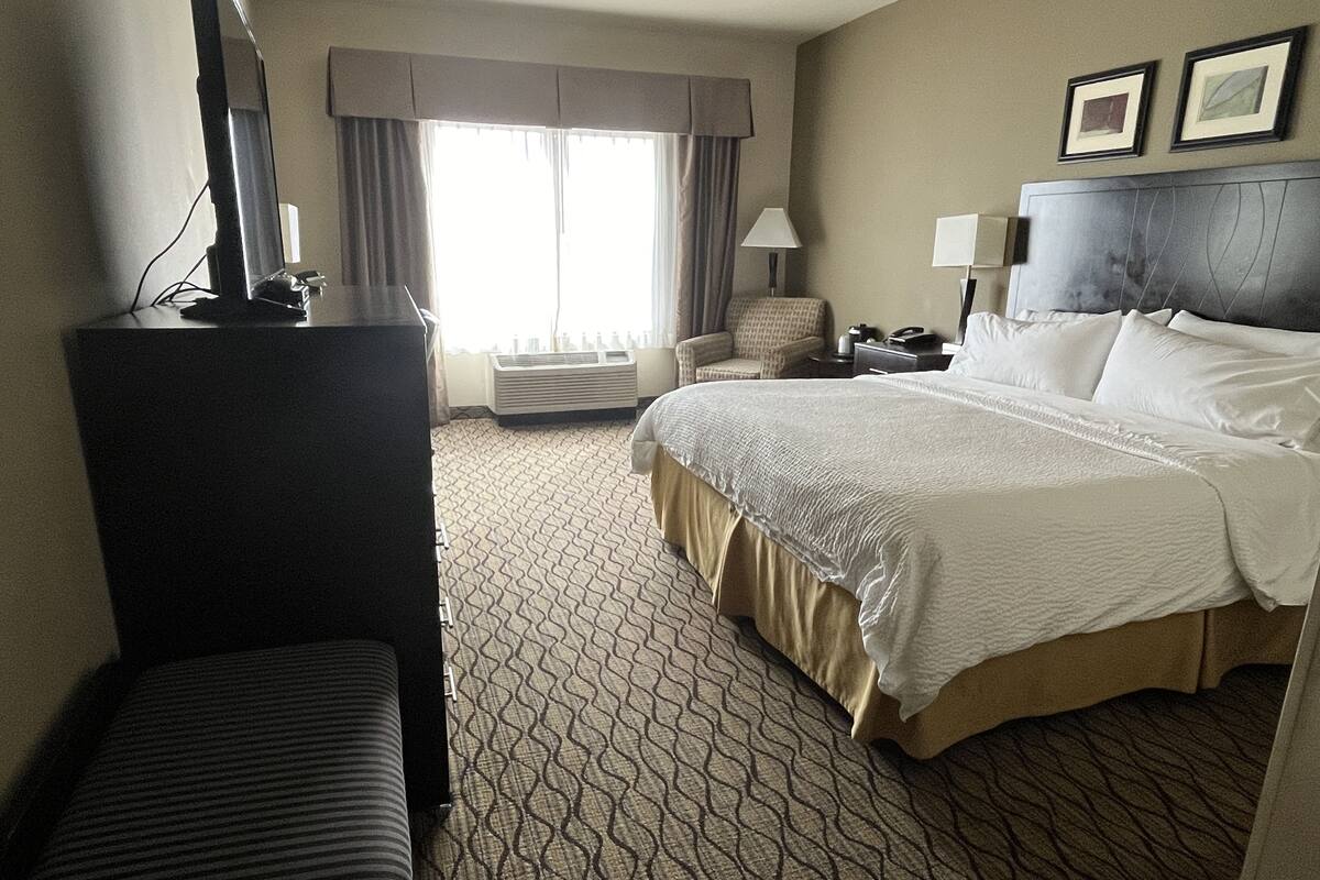 A hotel room with a bed, a desk, a chair, and a television.