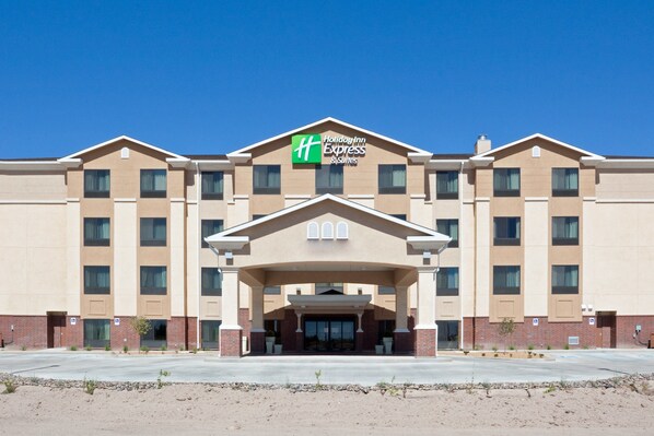 Welcome to the Holiday Inn Express & Suites, featuring a central entrance with columns and potted plants.