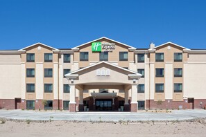 A Holiday Inn Express & Suites building with a symmetrical facade, multiple windows, and a central entrance with a pediment.