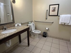 A bathroom with two sinks, a toilet, a handrail, a trash bin, and a framed picture on the wall. - Holiday Inn Express Hotel & Suites Deming Mimbres Valley by IHG (Deming)