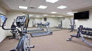 A gym with treadmills, elliptical machines, and free weights.