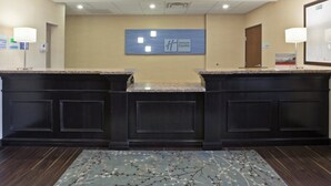 A reception area with a central desk, two side counters, a wall-mounted sign, and a patterned rug.