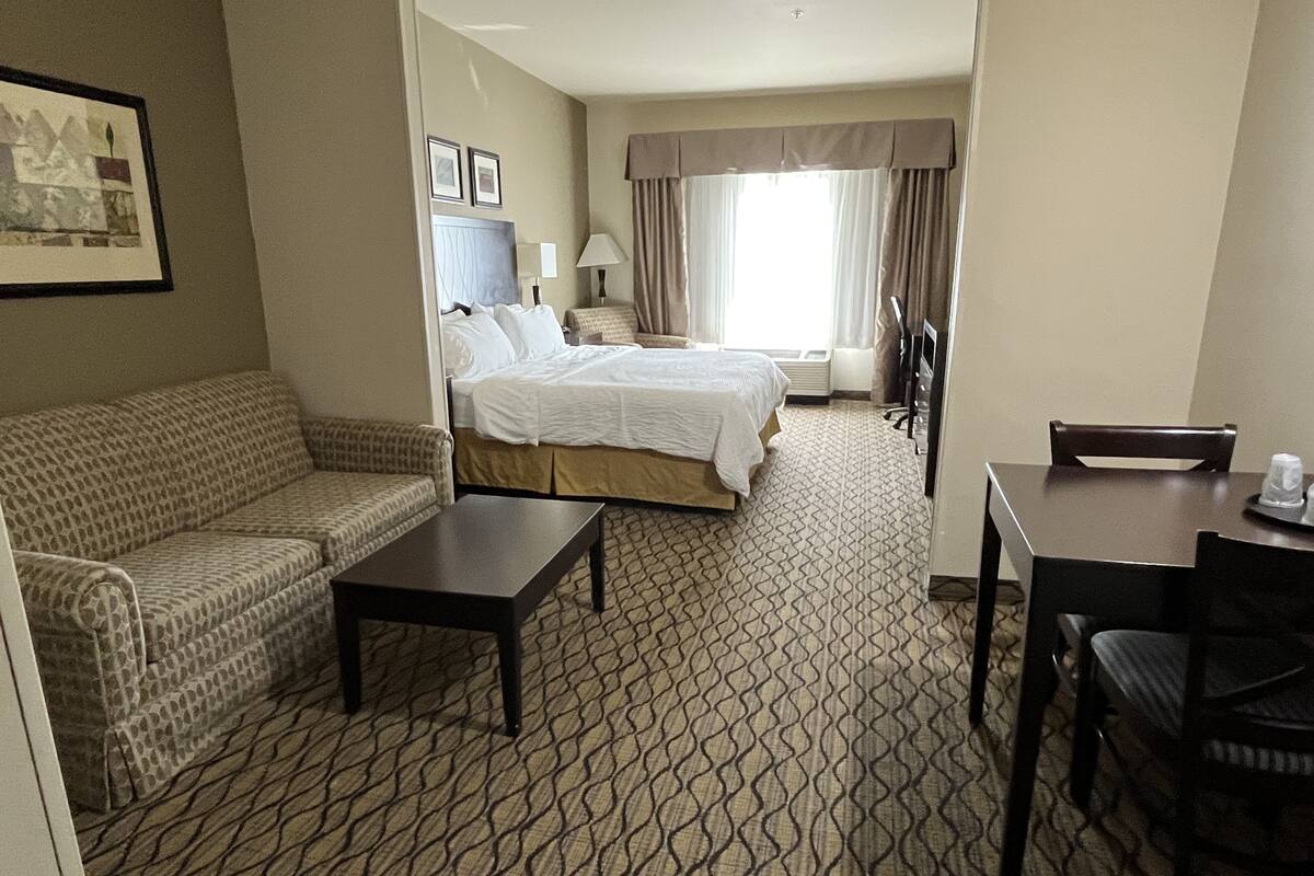 A hotel room with a bed, a sofa, a desk, and a dining table.