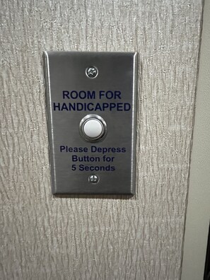 A sign indicating a room for handicapped individuals with a button to depress for 5 seconds. - Holiday Inn Express Hotel & Suites Deming Mimbres Valley by IHG (Deming)