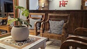 Un área de recepción con muebles de madera, una planta en maceta y una mesa de recepción con un letrero.
