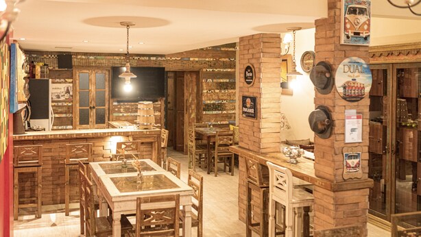 Un espacio de bar acogedor con mobiliario de madera, una pared de ladrillo y diferentes grifos de cerveza.