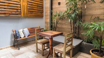 Une table et des chaises en bois se trouvent dans une pièce dont le sol est également en bois, et un banc agrémenté de coussins y est installé.
