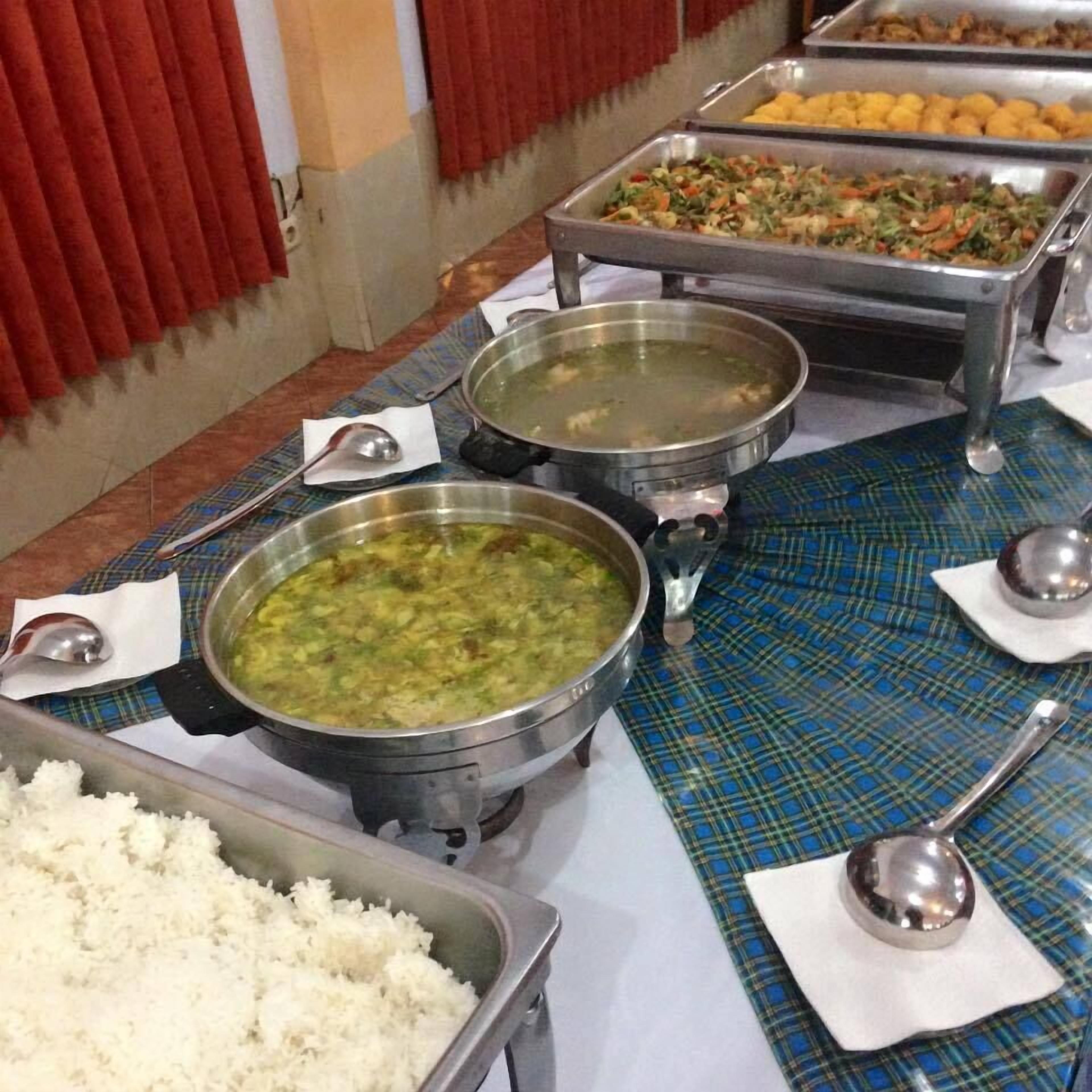 A buffet setup with various dishes including rice, soup, and mixed vegetables.