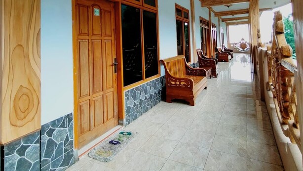 A corridor with wooden doors, stone accents, and a tiled floor. - Hotel Nadia Bromo (Sukapura)