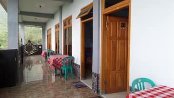 Un pasillo con mesas y sillas, puertas de madera y suelo de baldosas.