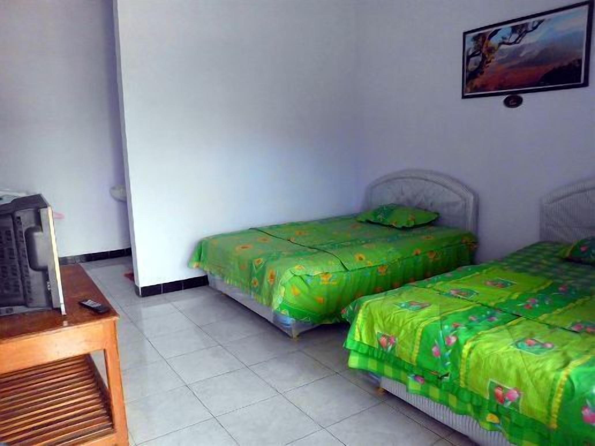 Una habitación con dos camas, televisión y una mesa de madera.