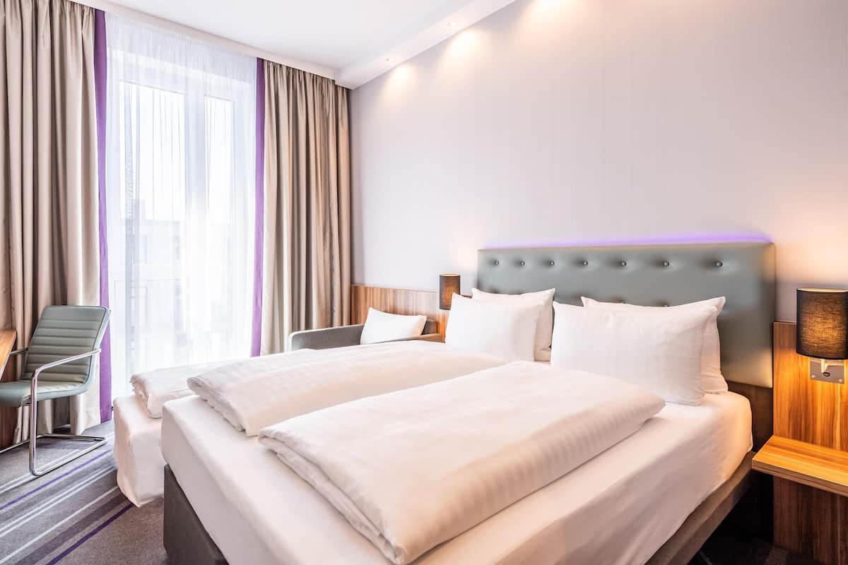 Ein Hotelzimmer mit einem großen Bett, einem Sessel, einem Nachttisch und einer Lampe.
