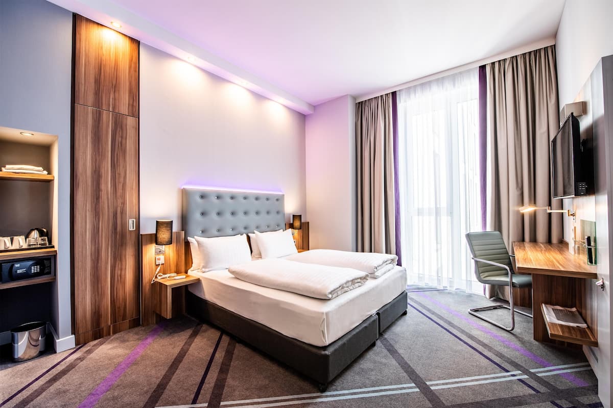 Ein Hotelzimmer mit Bett, Schreibtisch, Fernseher und Minibar.