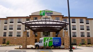 A Holiday Inn Express & Suites building with a covered entrance, a truck with the hotel branding, and a clear sky. - Holiday Inn Express & Suites St Louis Airport by IHG (St. Louis)
