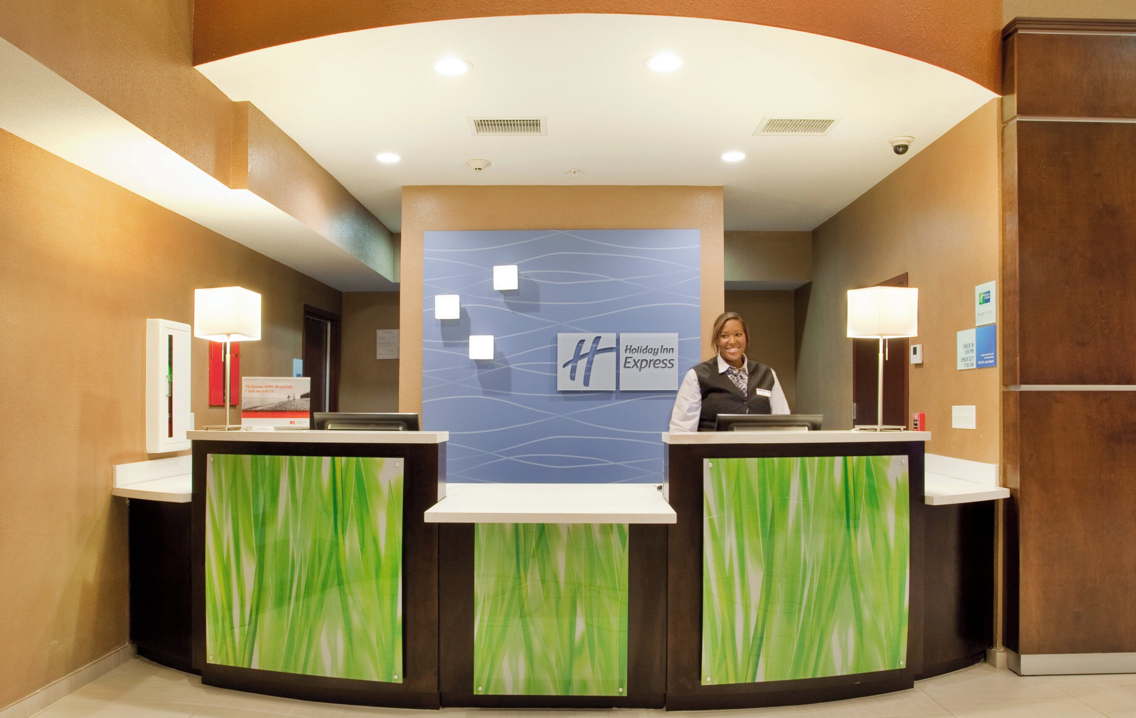 A reception desk with a Holiday Inn Express sign, two receptionists, and a modern interior design.