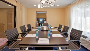 A conference room with a long table, chairs, water bottles, a phone, and a notepad. - Holiday Inn Express & Suites St Louis Airport by IHG (St. Louis)