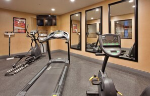 A gym with treadmills, stationary bikes, and a mirrored wall.