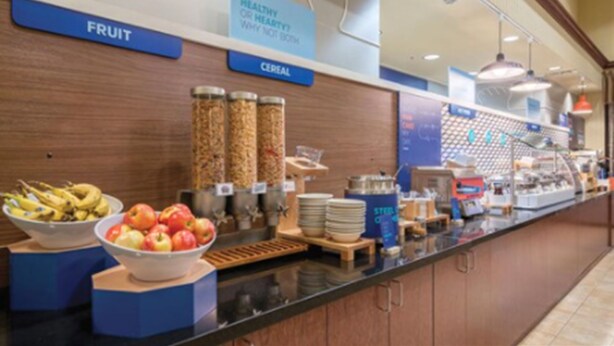 A breakfast buffet with labeled sections for fruit and cereal. - Holiday Inn Express & Suites St Louis Airport by IHG (St. Louis)