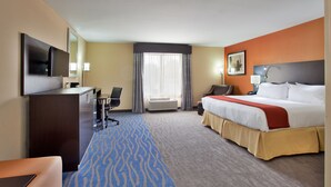 A hotel room with a bed, desk, chair, TV, and a large window with curtains. - Holiday Inn Express & Suites St Louis Airport by IHG (St. Louis)