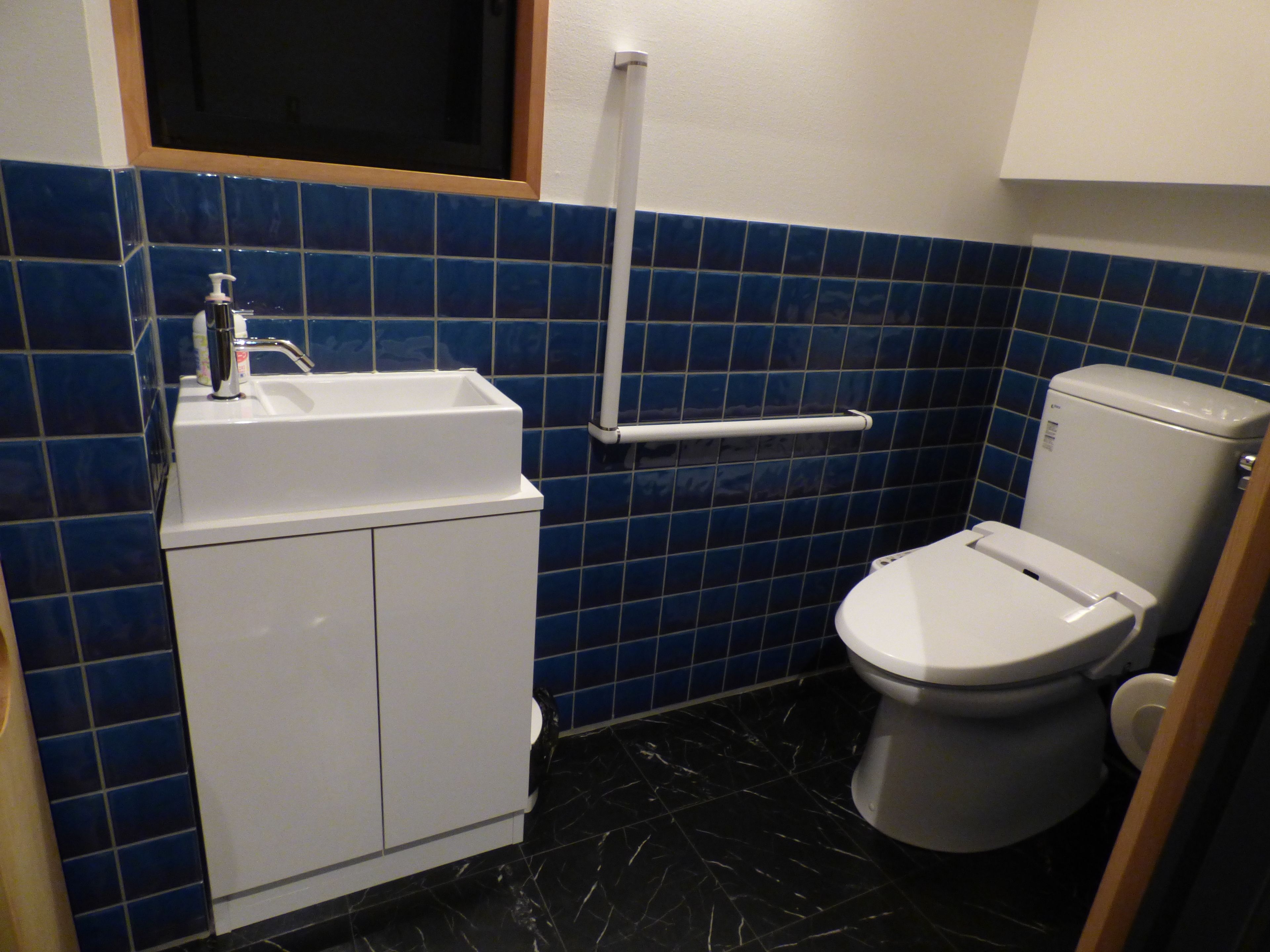 Un baño con un lavabo blanco, un inodoro y paredes con azulejos azules.