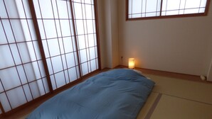A room with tatami flooring, a blue mattress, and a shoji screen.