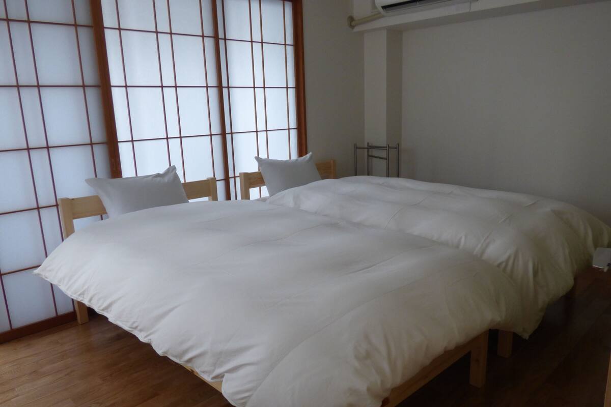 A room with a large bed, wooden headboard, and a sliding shoji screen.