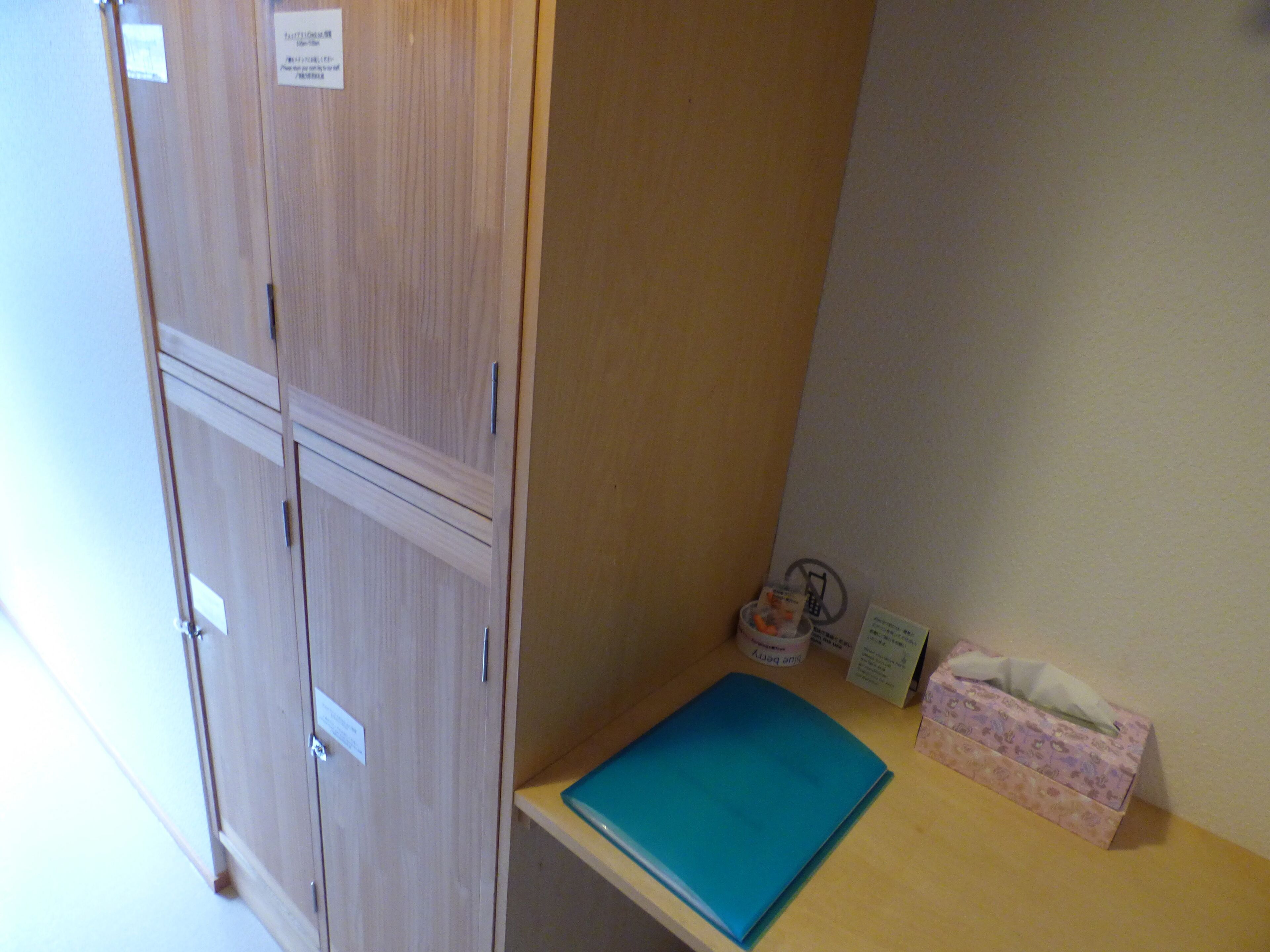 A room with wooden cabinets, a small table with a blue folder, and a tissue box.