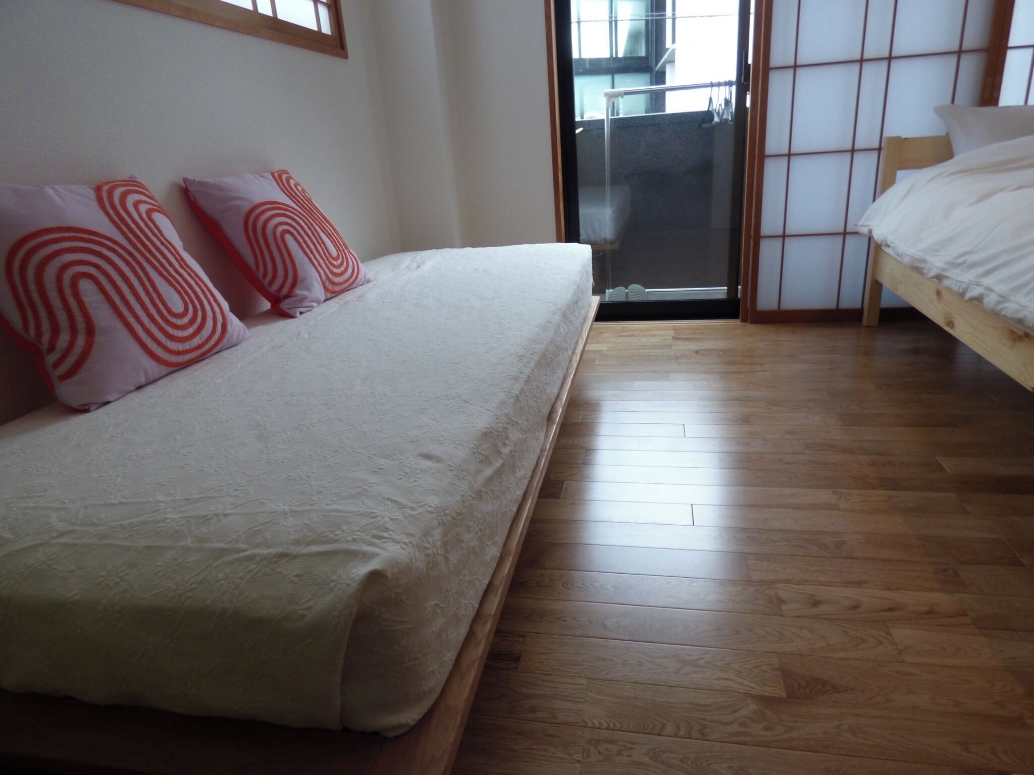 Une chambre à coucher avec un lit, un plancher en bois et une porte-fenêtre coulissante donnant sur un balcon.