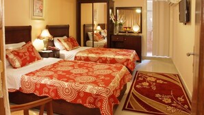 Ein Hotelzimmer mit zwei Betten, einem Schreibtisch, einem Spiegel und einem Fernseher.