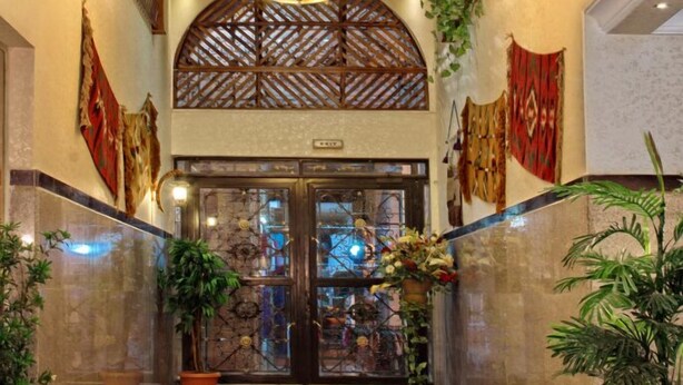 Eine Hotelhalle mit einem Kronleuchter, Zimmerpflanzen und einer Rezeption.