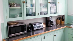 A kitchen with light green cabinets, a microwave, toaster, and coffee maker on the countertop. - Sauerdough Lodging (Seward)