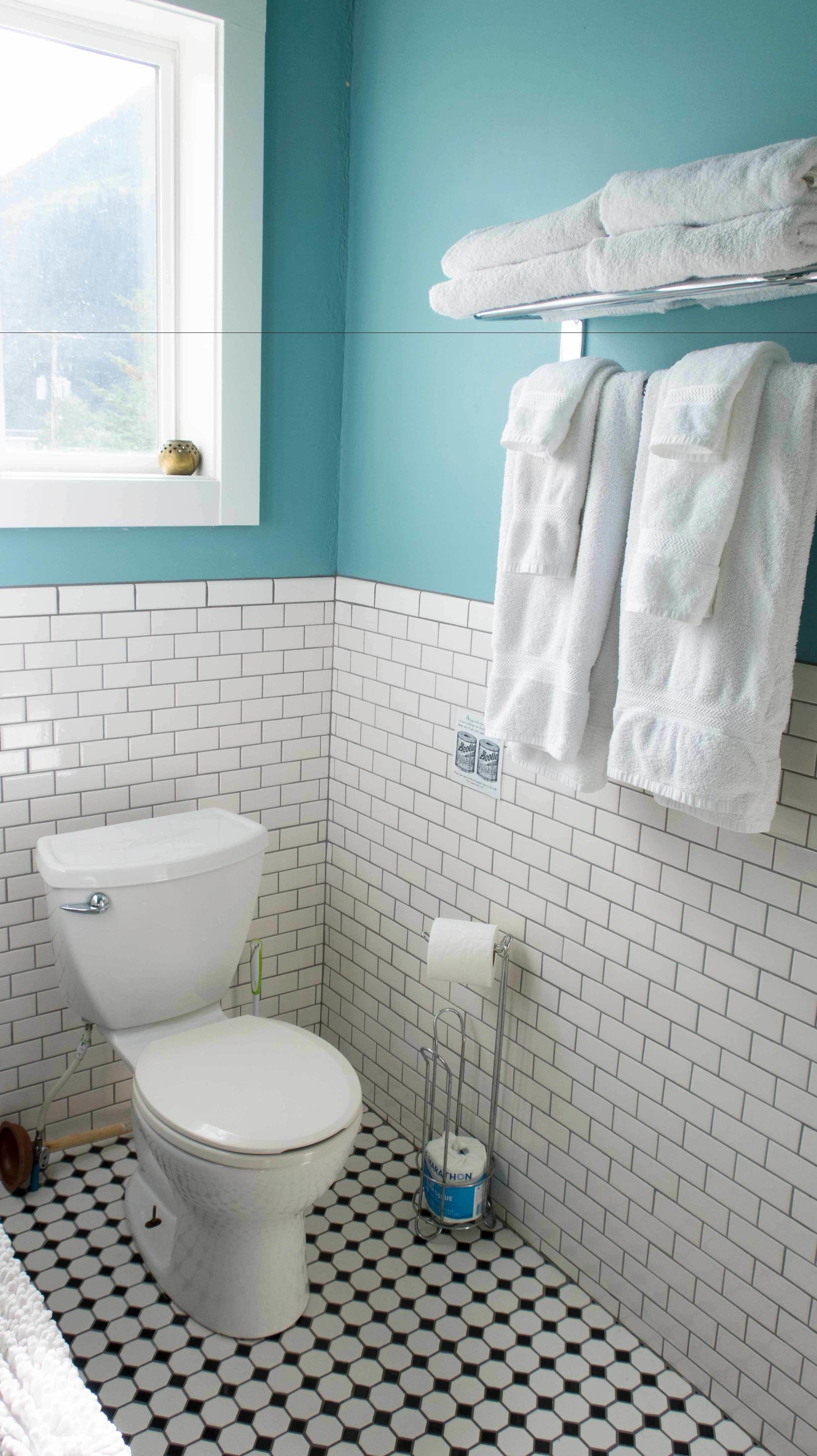 Une salle de bain équipée de toilettes, d’un porte-serviettes avec des serviettes, d’un support à papier toilette et d’une fenêtre donnant sur un espace verdoyant.