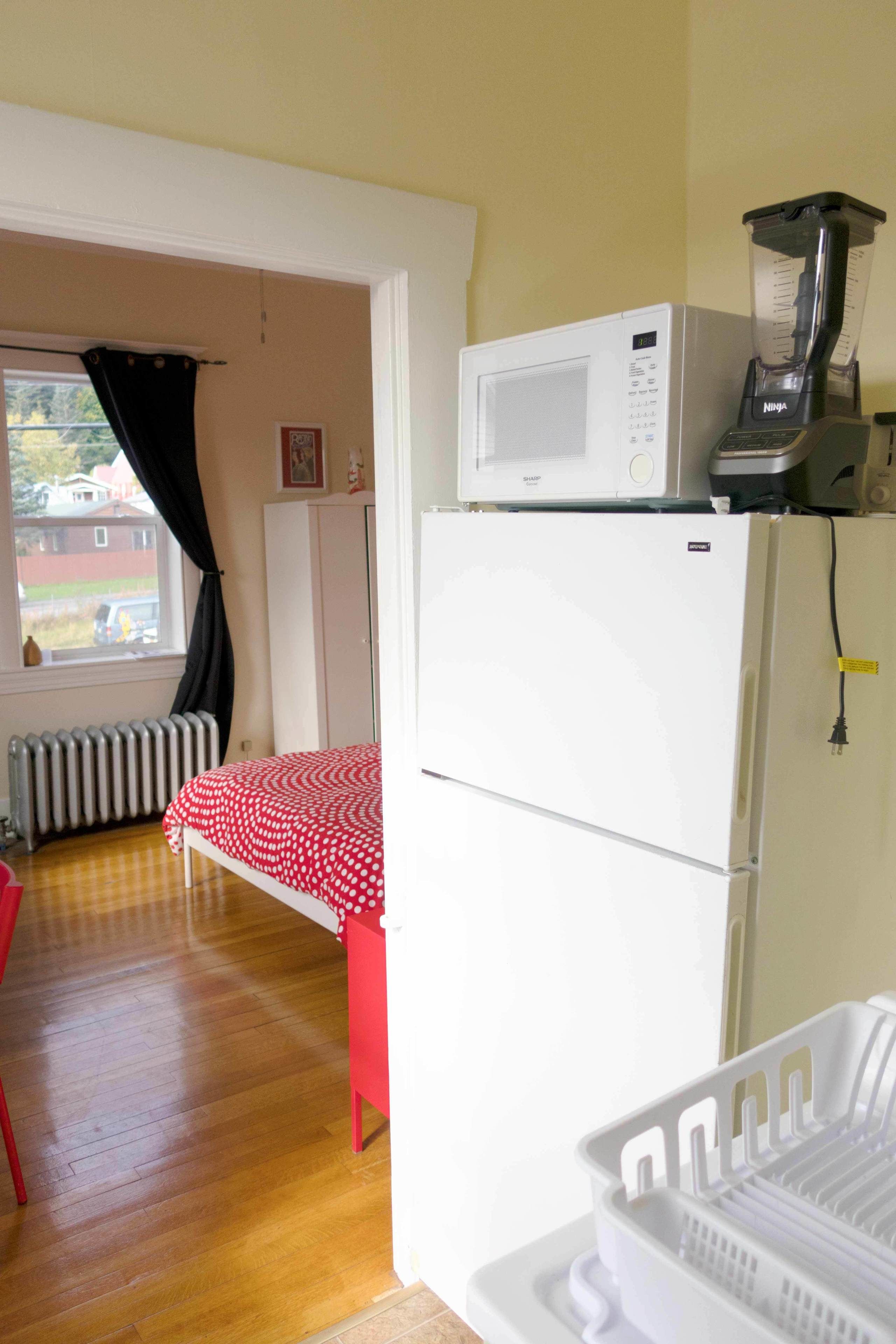 Una cocina compacta con refrigerador, microondas y licuadora.