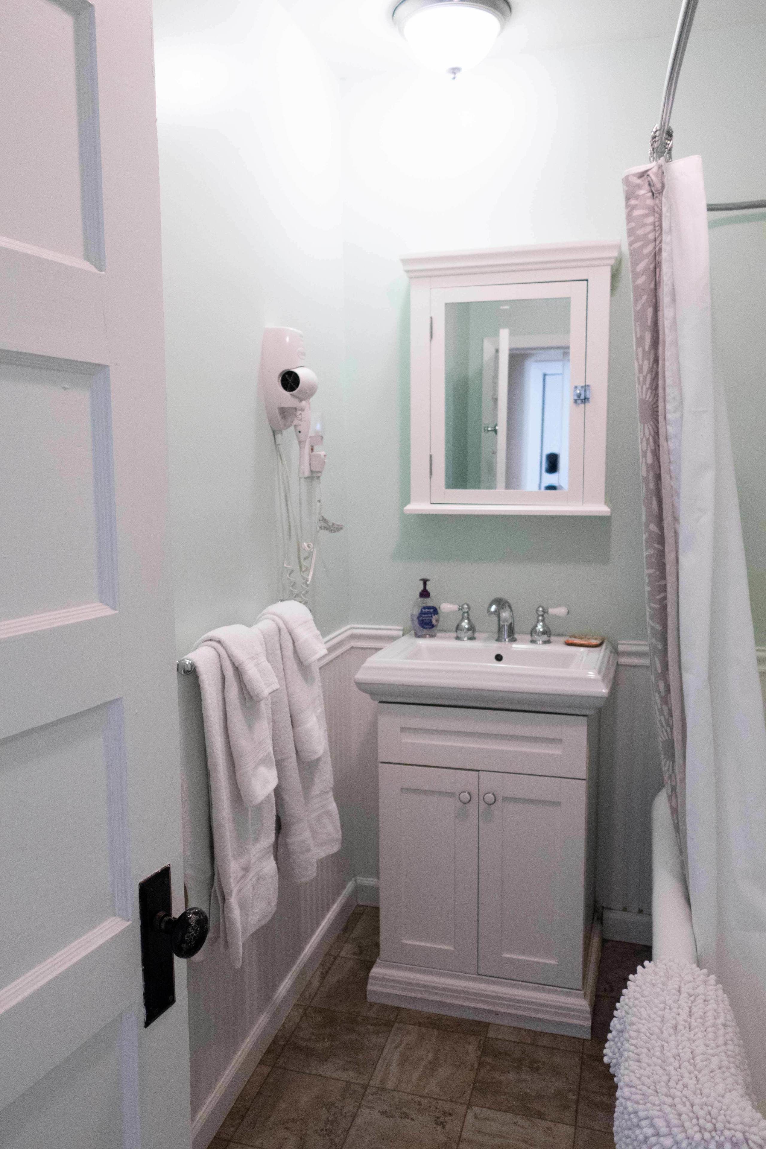 A bathroom with a white sink, mirror, and towel rack.