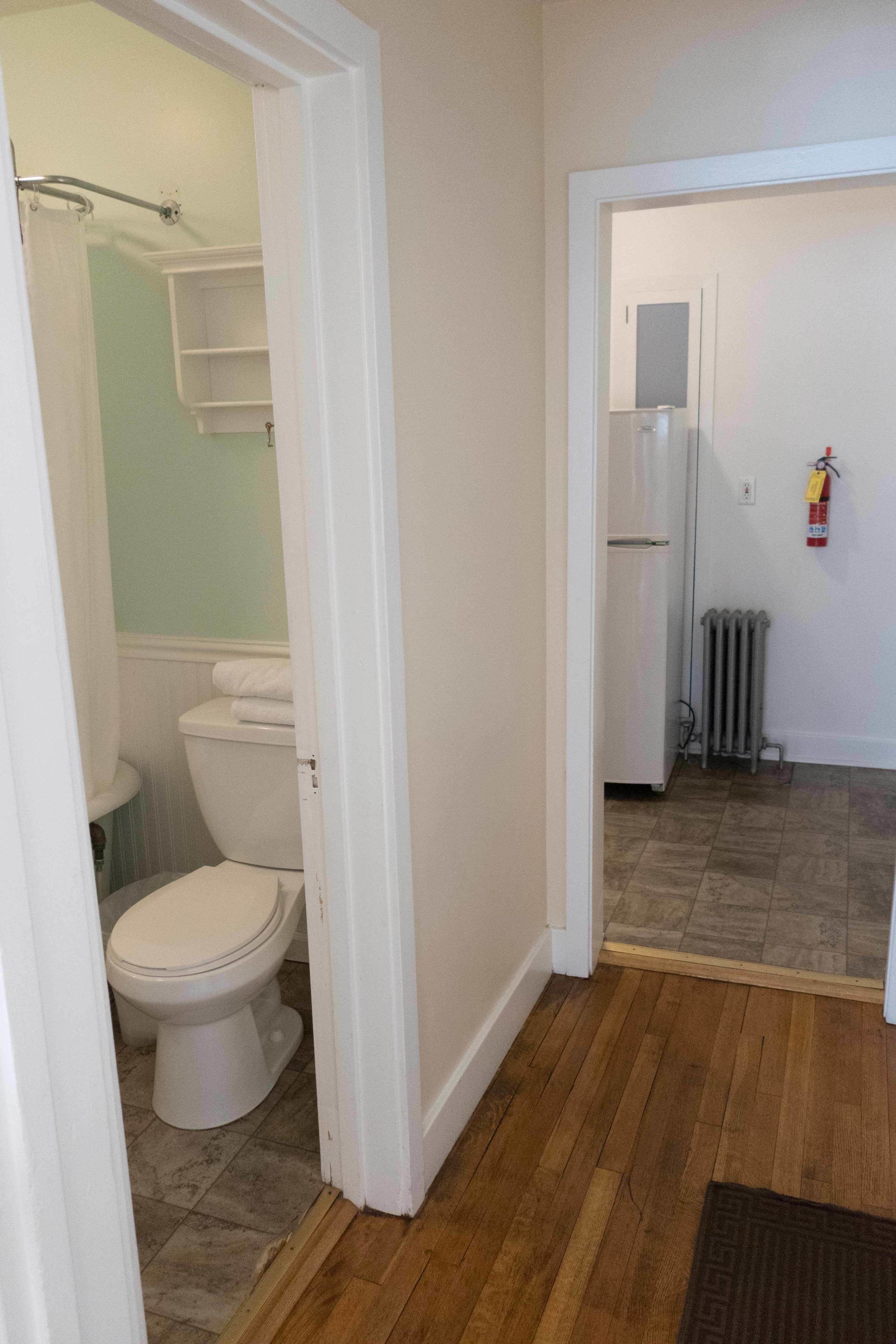 A bathroom with a toilet, a shower, and a white cabinet.