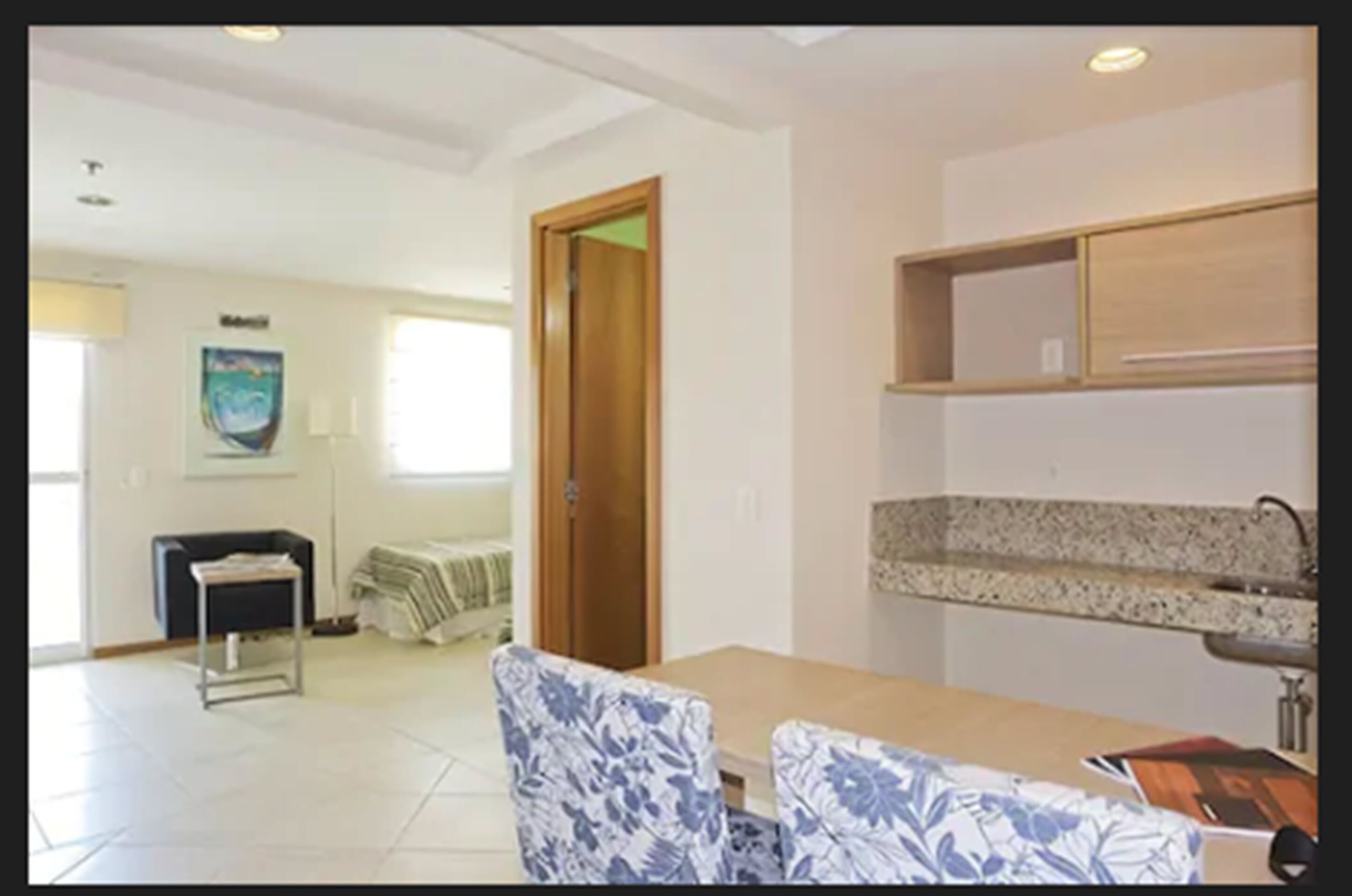 A dining area with a table and chairs, a kitchen counter, and a door leading to another room.