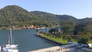 A marina with boats docked, a dock extending into a body of water, and a hill with dense vegetation in the background. - Porto Marina Mont Blanc Resort (Mangaratiba)