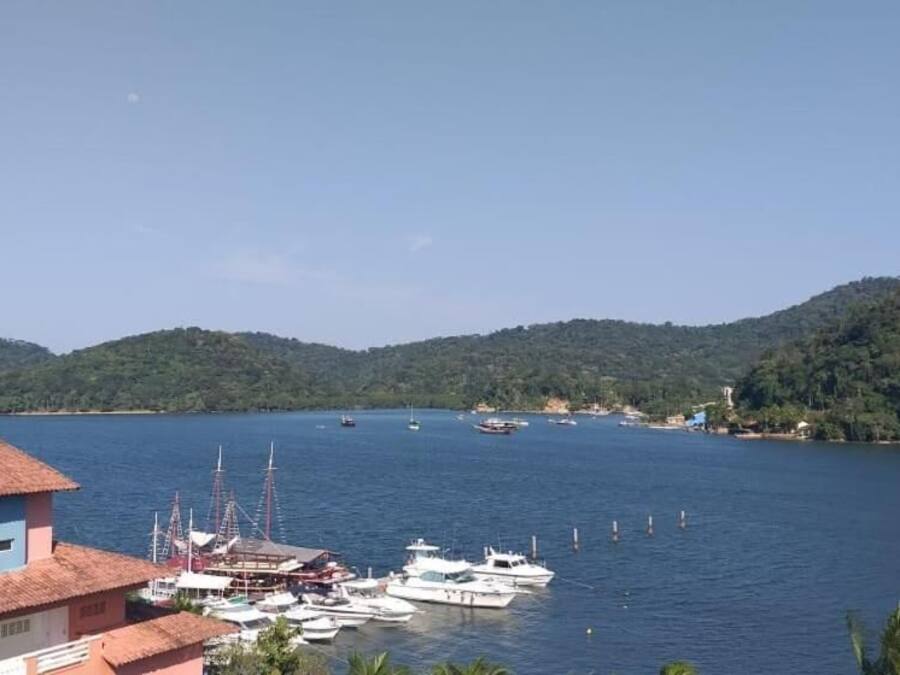 A coastal marina with boats docked, surrounded by hills and a clear sky.
