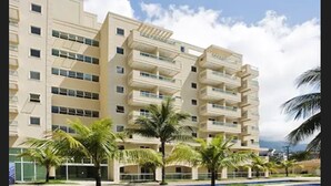 A multi-story hotel with balconies, a swimming pool, and palm trees. - Porto Marina Mont Blanc Resort (Mangaratiba)