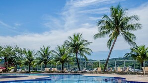 A pool area with lounge chairs and palm trees. - Porto Marina Mont Blanc Resort (Mangaratiba)