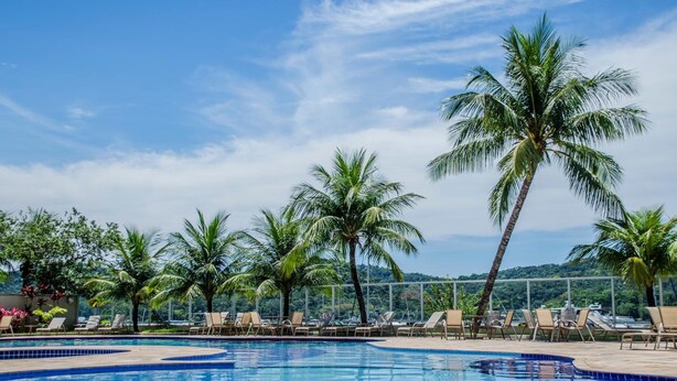 A pool area with lounge chairs and palm trees. - Porto Marina Mont Blanc Resort (Mangaratiba)