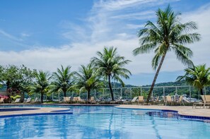 Un área de piscina con sillas de descanso y palmeras.