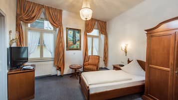 Een hotelkamer met een bed, een televisie, een stoel, een klein tafeltje en een kledingkast.