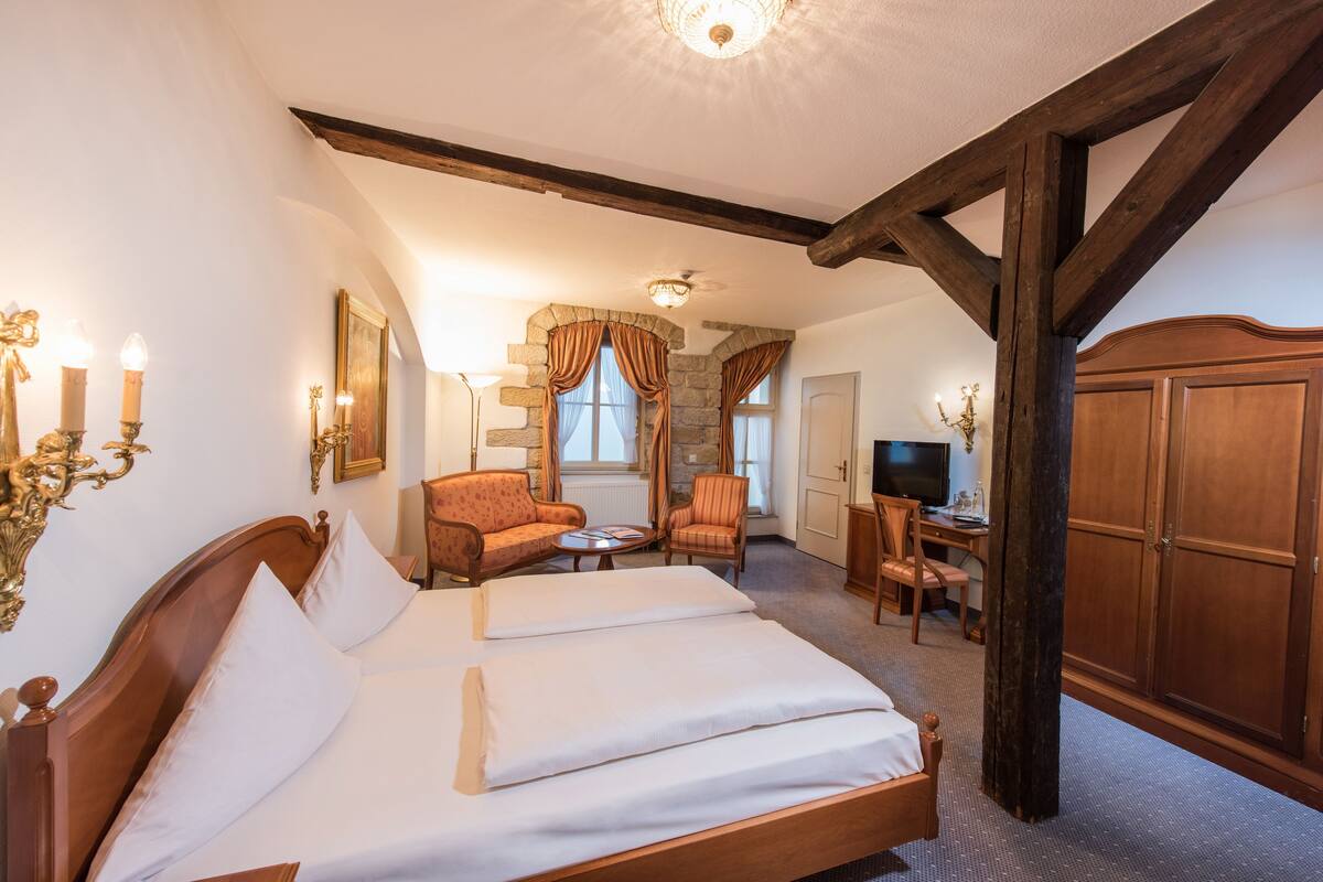 Una habitación de hotel con una cama grande, un escritorio, una silla y un televisor.