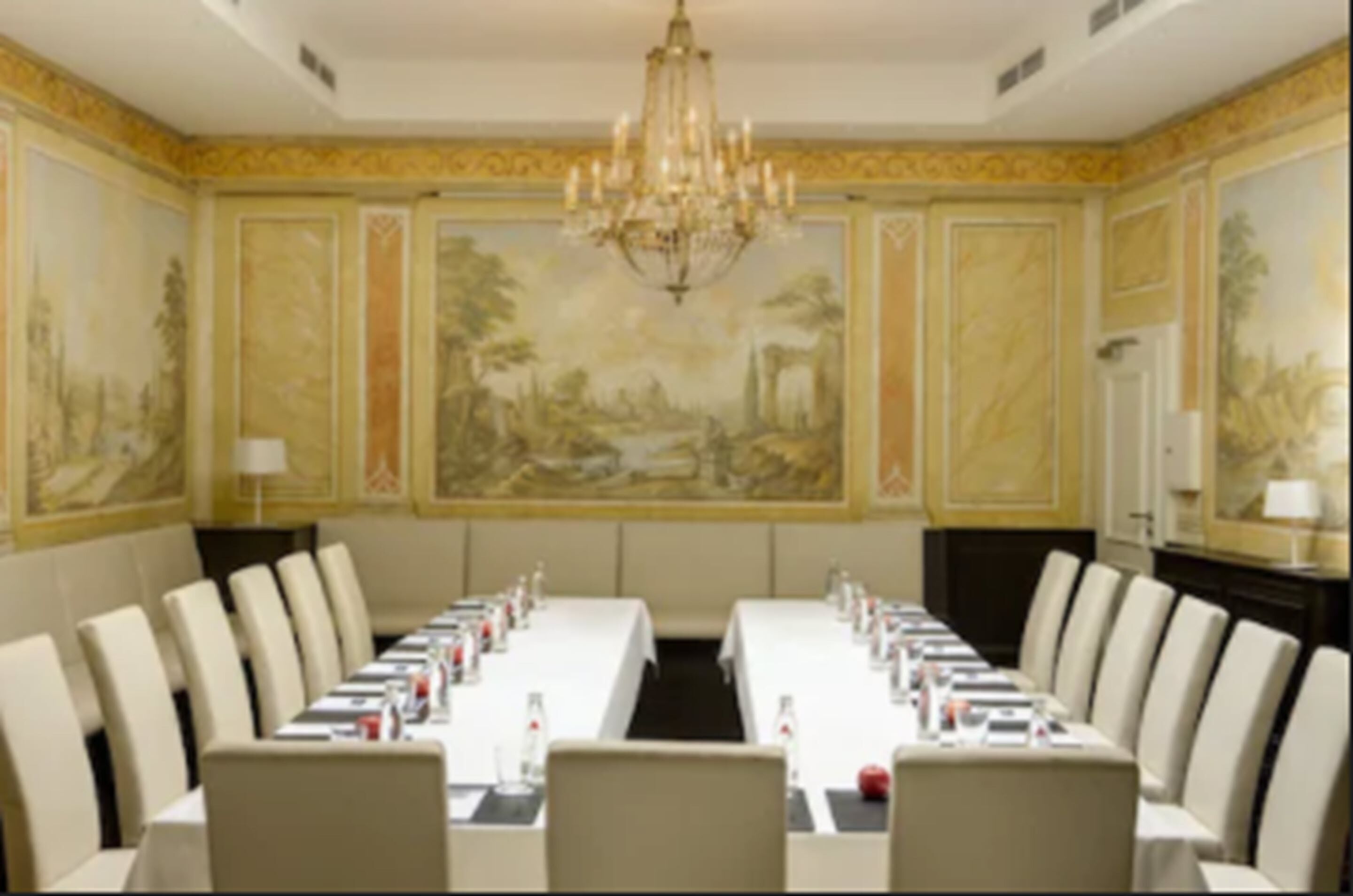 Une salle de conférence avec une longue table, des chaises et un lustre.