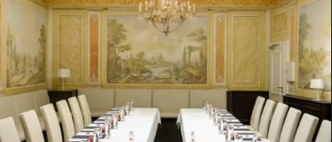 Une salle de conférence avec une longue table, des chaises et un lustre.