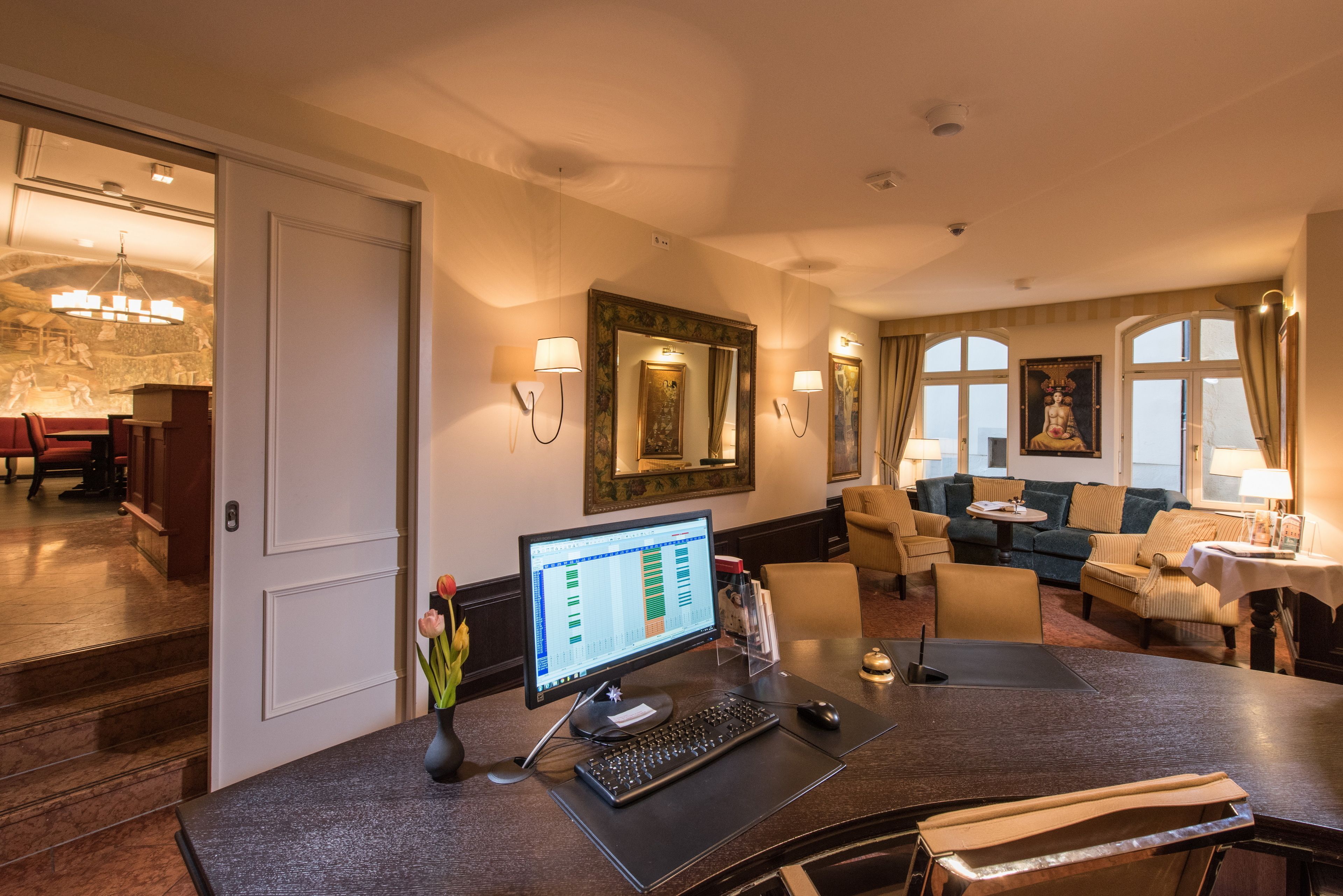 A hotel room with a desk, computer, and a seating area with a sofa and armchairs.