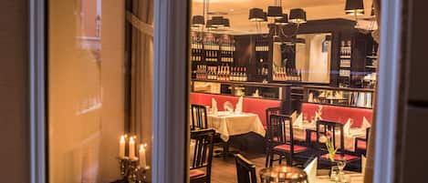 Un restaurante con una bodega de vinos, cabinas rojas y mesas iluminadas con velas.