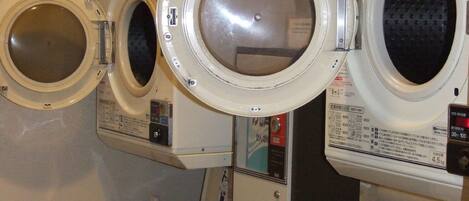 A wall-mounted laundry machine with a control panel and a small wooden cabinet below.